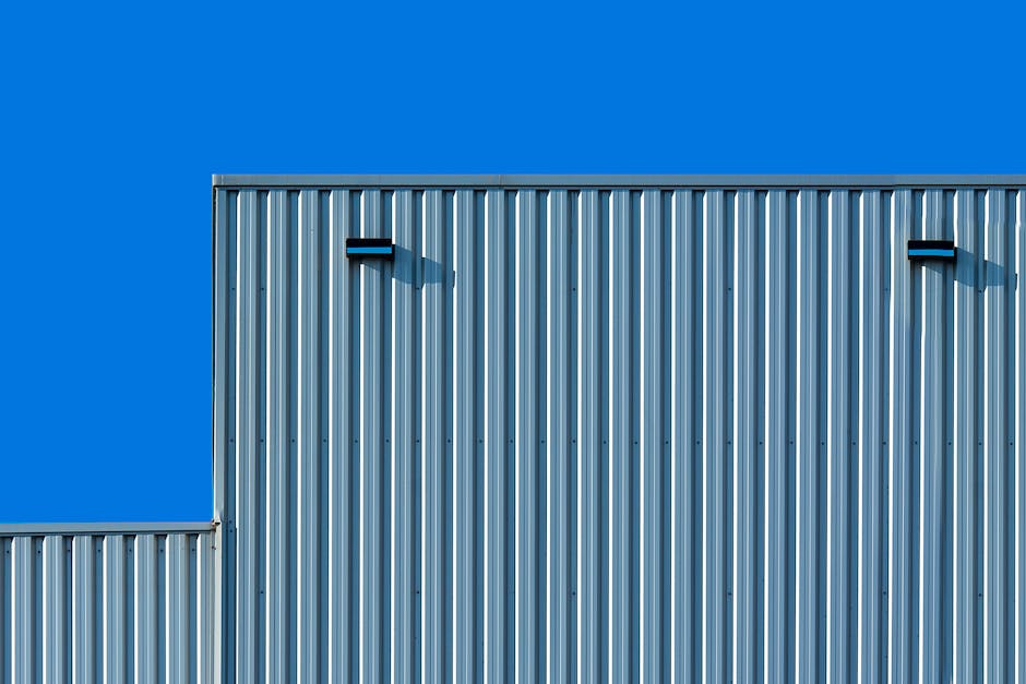 Corrugated metal building facade against a vibrant blue sky, minimalist design.